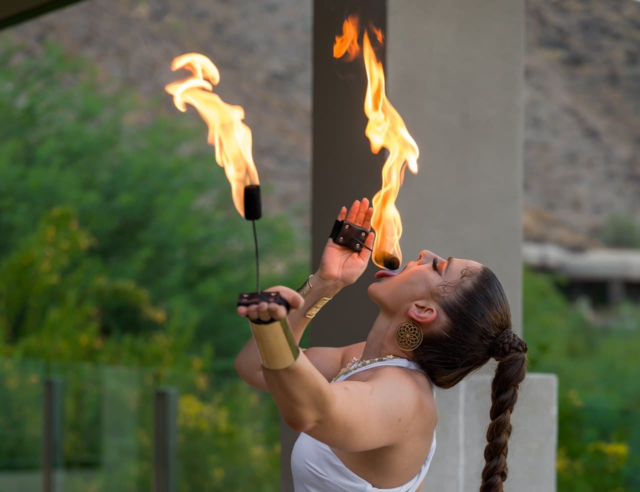 A fire performer in white on the estate terrace at dusk